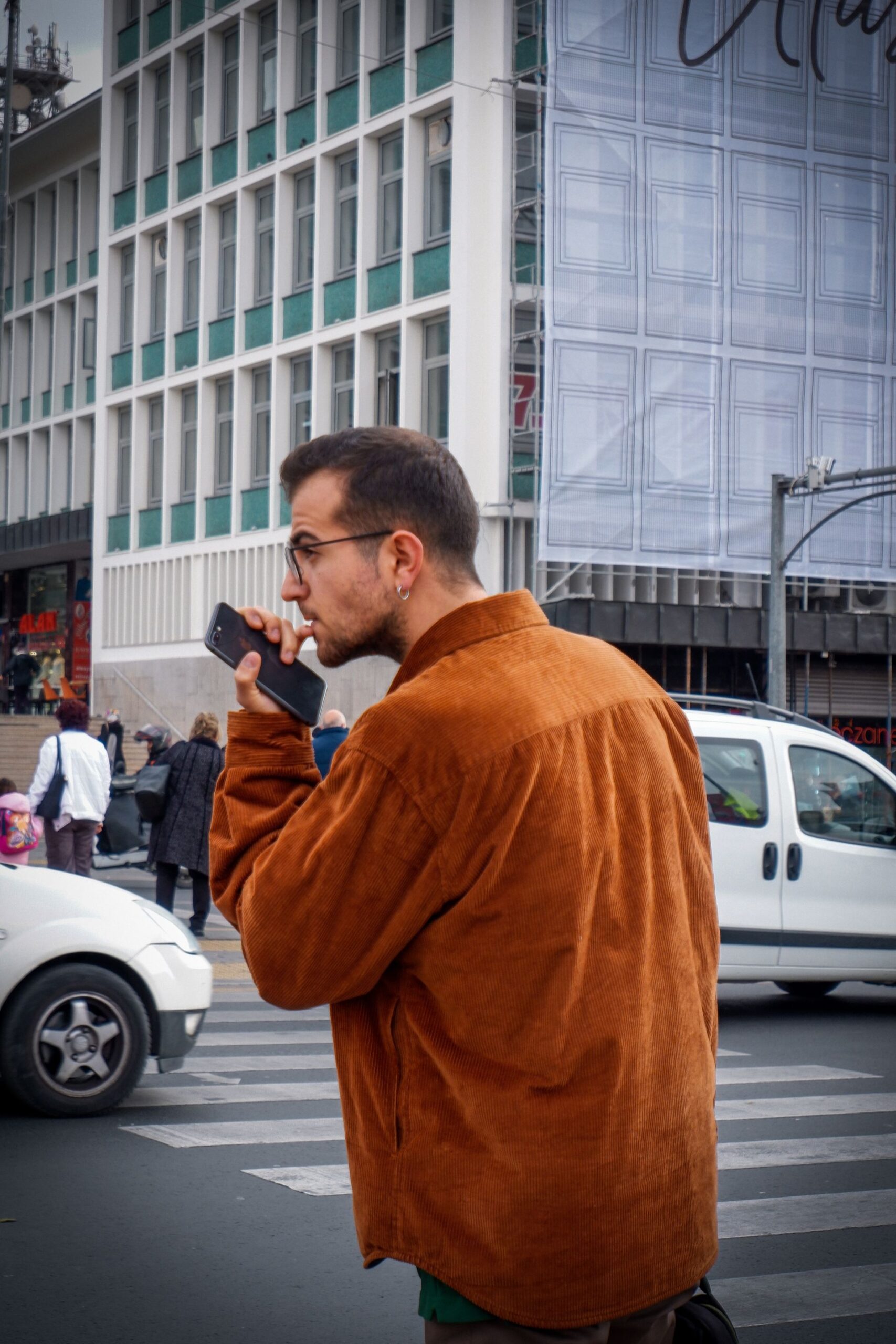 Person using a smartphone while crossing a busy city street