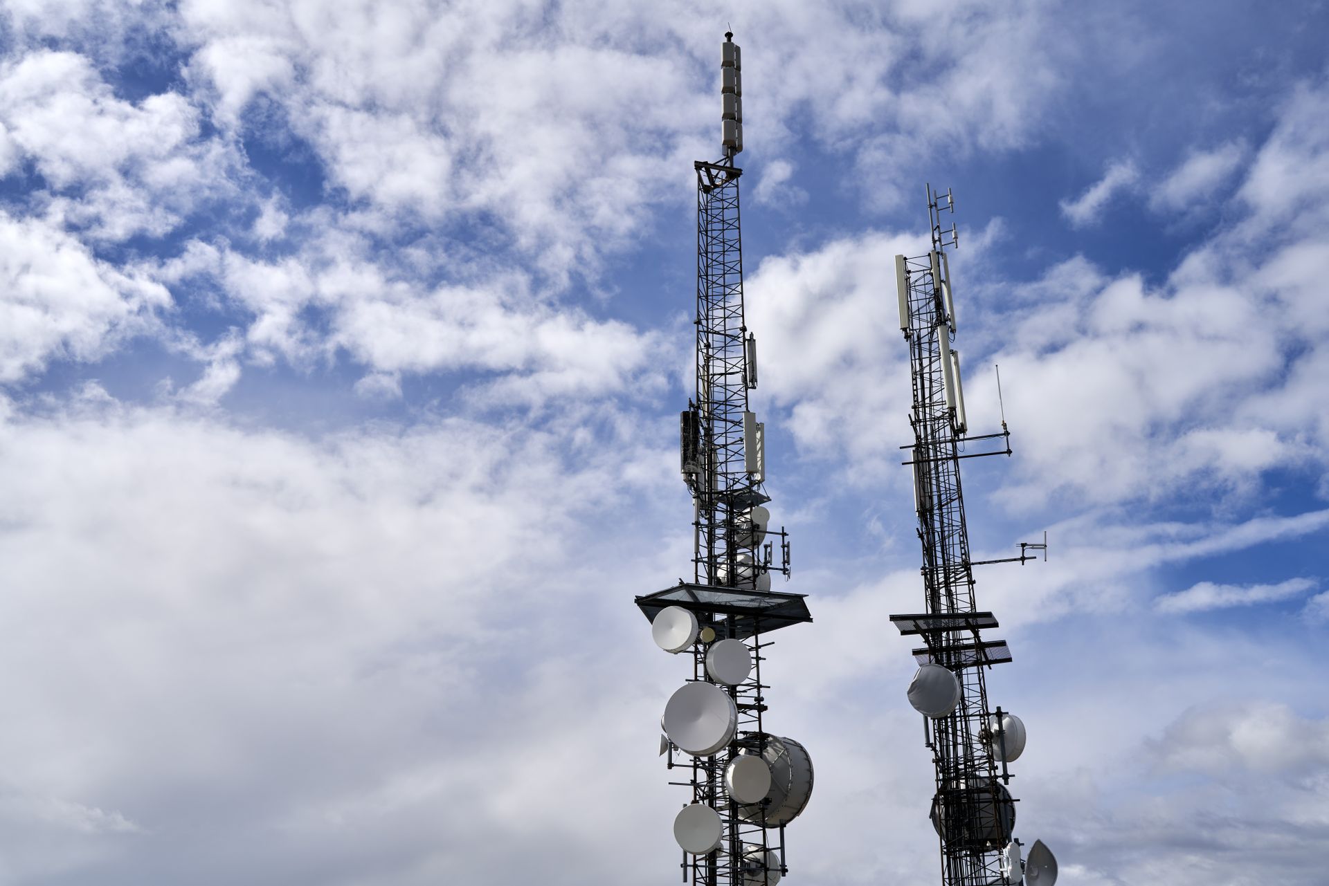 Telecommunication towers with antennas and dishes under a bright sky